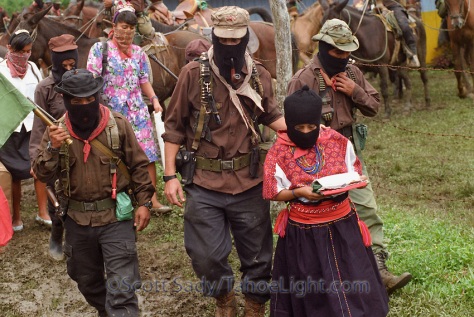 Zapatista sub commander Marcos leads Zapatista commander Ramona, to a waiting vehicle for her journey to Mexico City, 1996. To the right of Marcos is major Moises, and to the left comander Tacho.